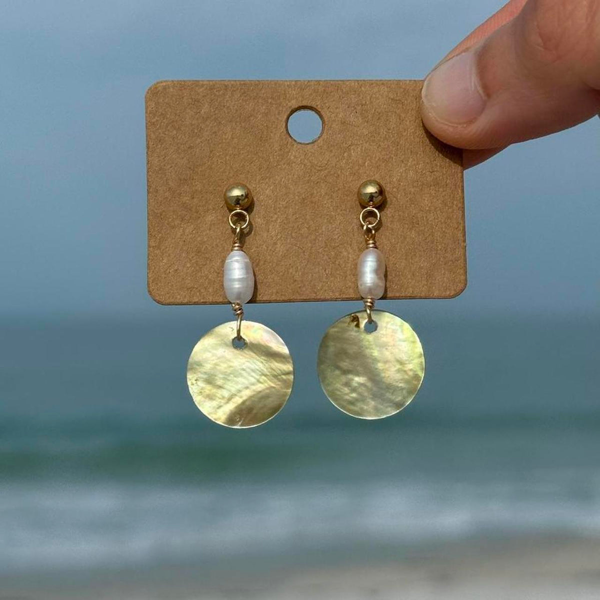Close view of gold Pearl Tide Earrings with mother-of-pearl discs