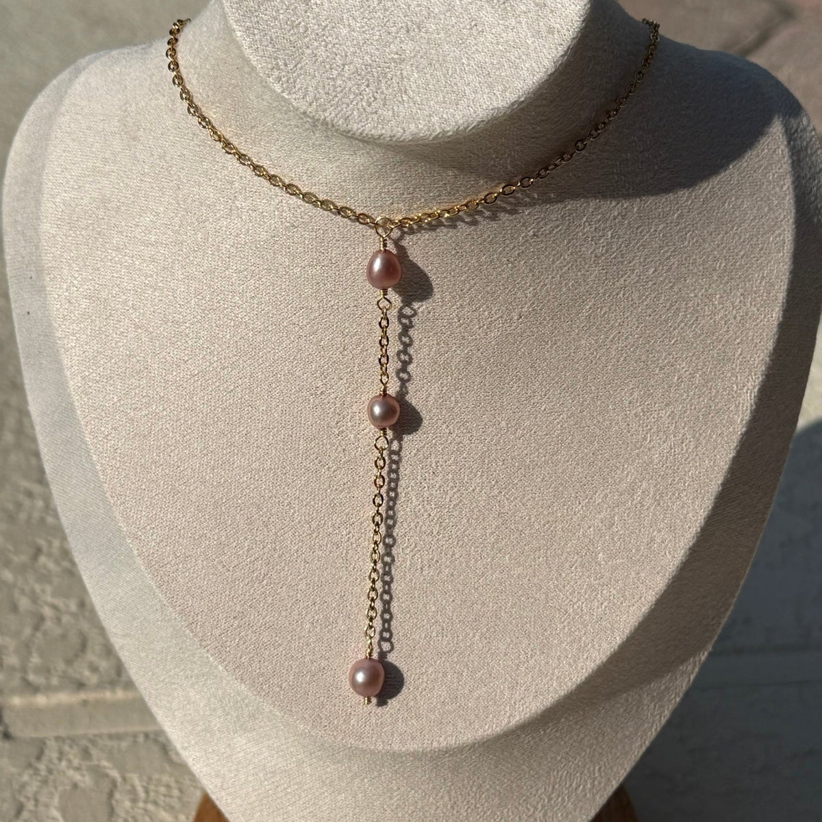 Gold-tone lariat necklace with blush pink pearl accents