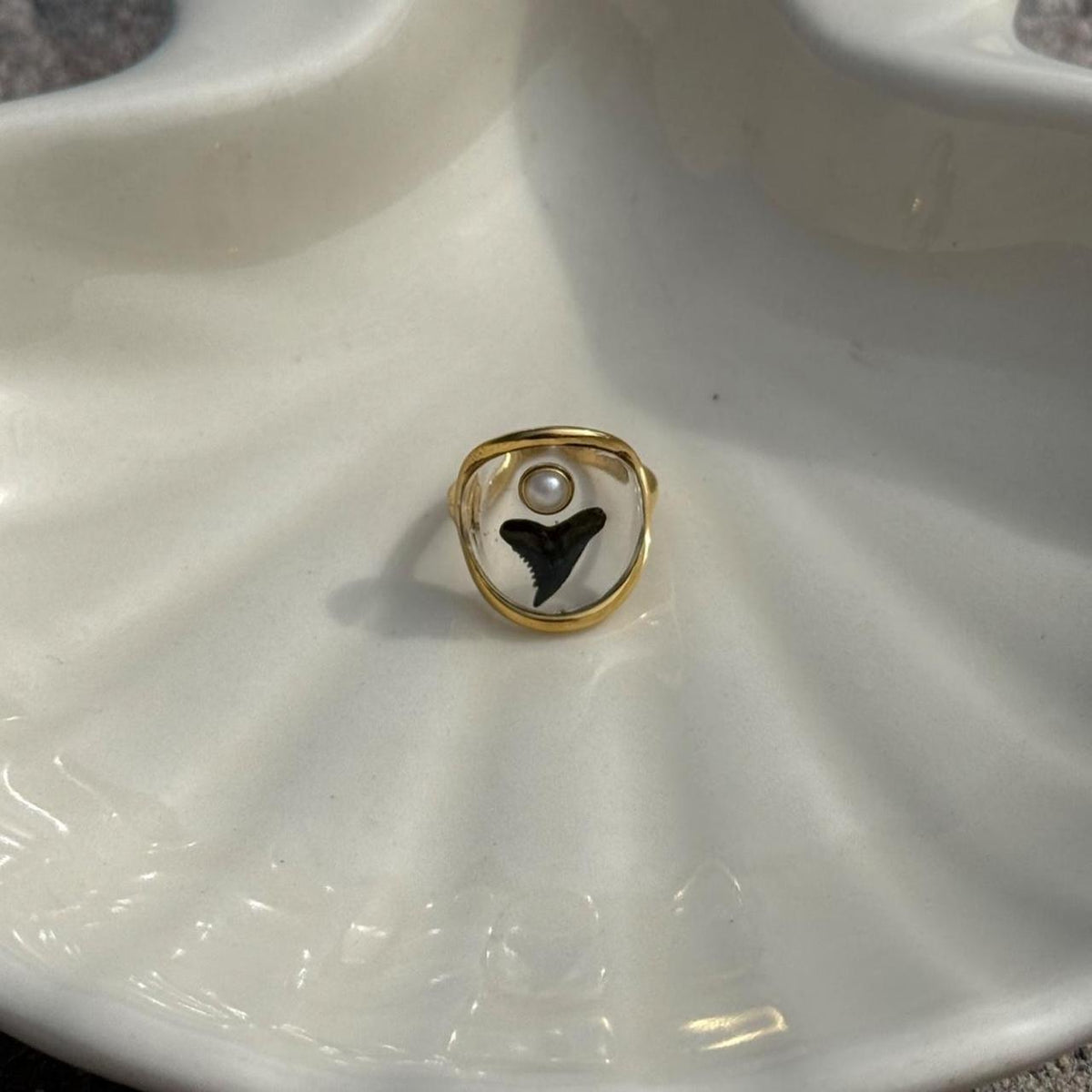 Shark tooth and pearl resin ring displayed on ivory ceramic
