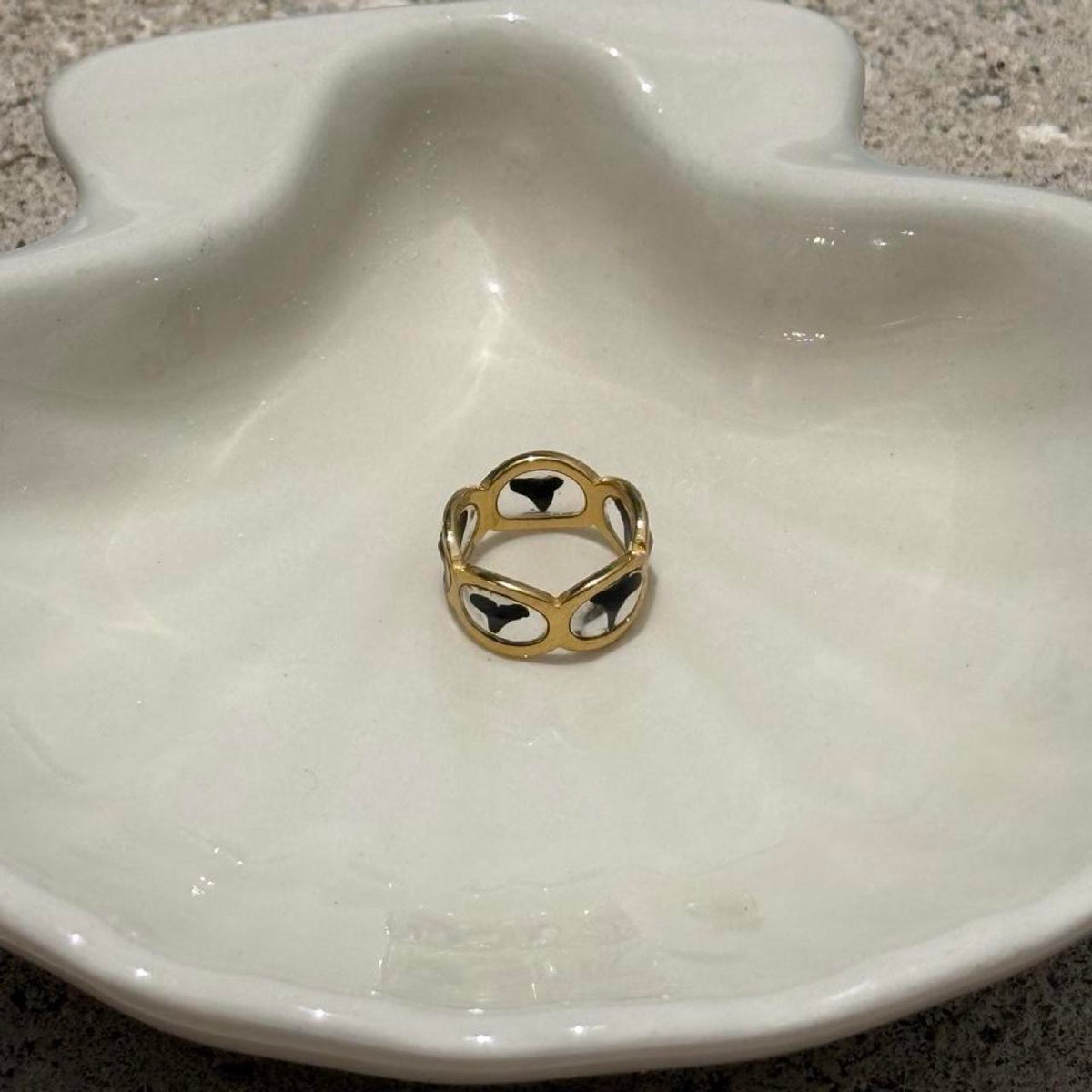 Gold shark tooth resin ring on coastal jewelry dish