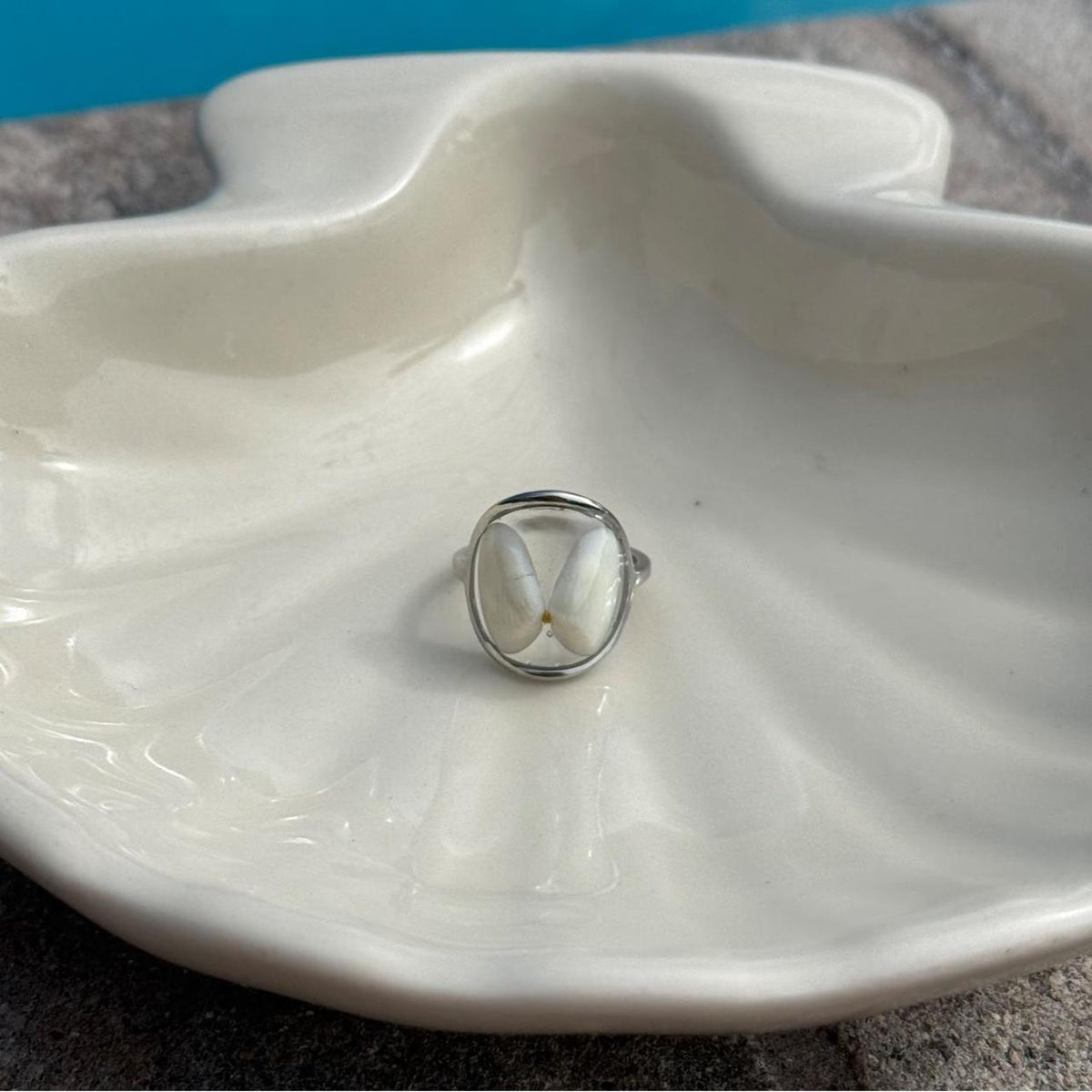 White butterfly resin ring displayed on ivory ceramic