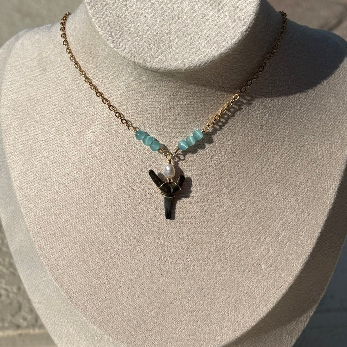 Blue Current Shark Tooth Necklace displayed on a jewelry bust