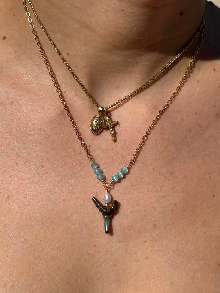 Close worn view of aqua bead shark tooth necklace