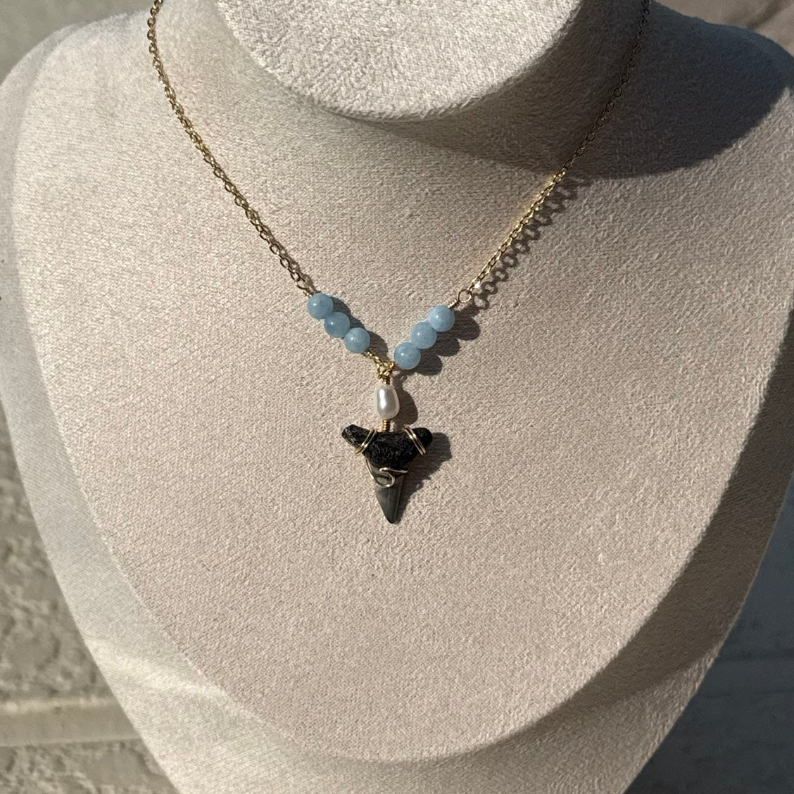 Close view of gold-tone shark tooth necklace