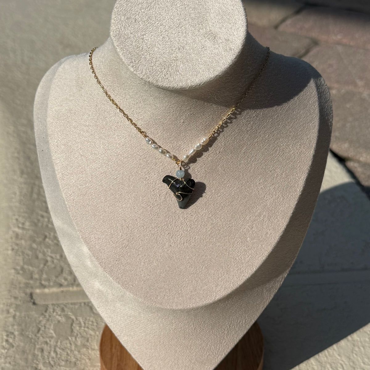 Gold-tone pearl and shark tooth necklace on display