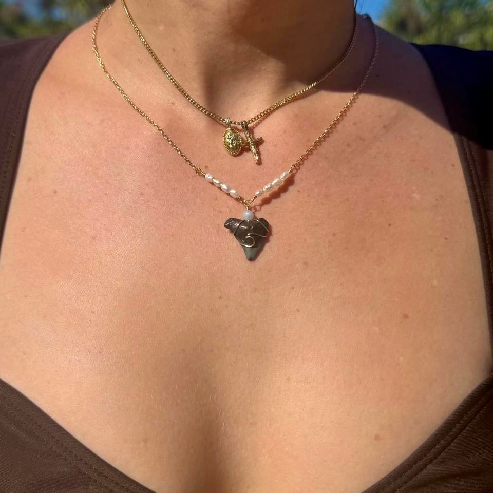 Gold-tone pearl shark tooth necklace worn in sunlight