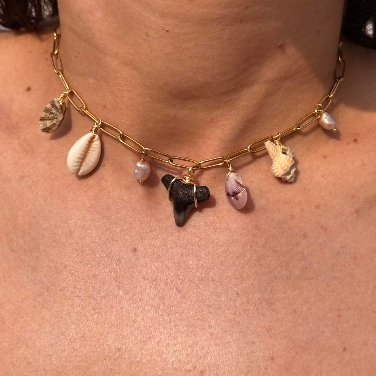 Close view of shark tooth shell and pearl charm necklace