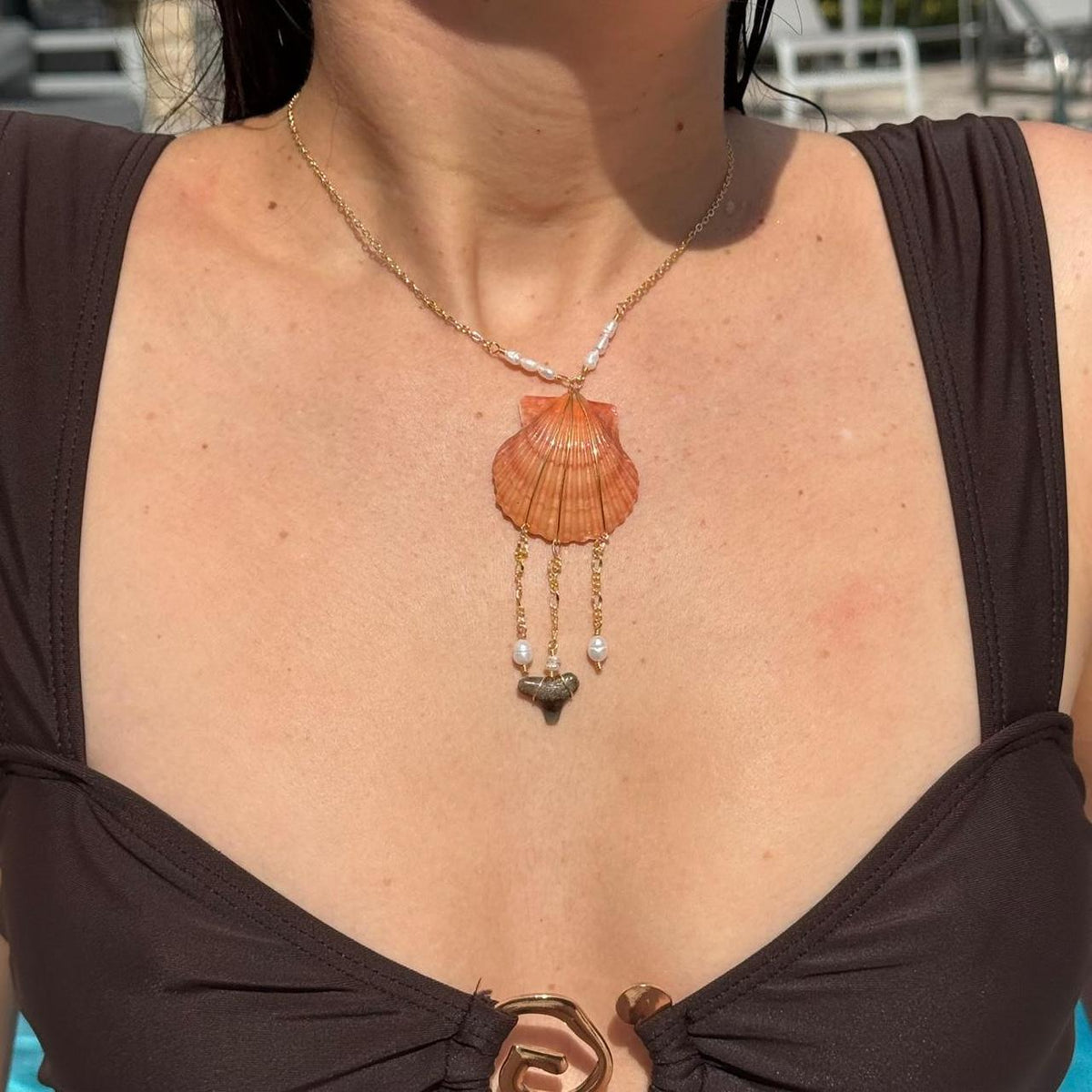 Handmade orange scallop shell and shark tooth necklace worn in sunlight