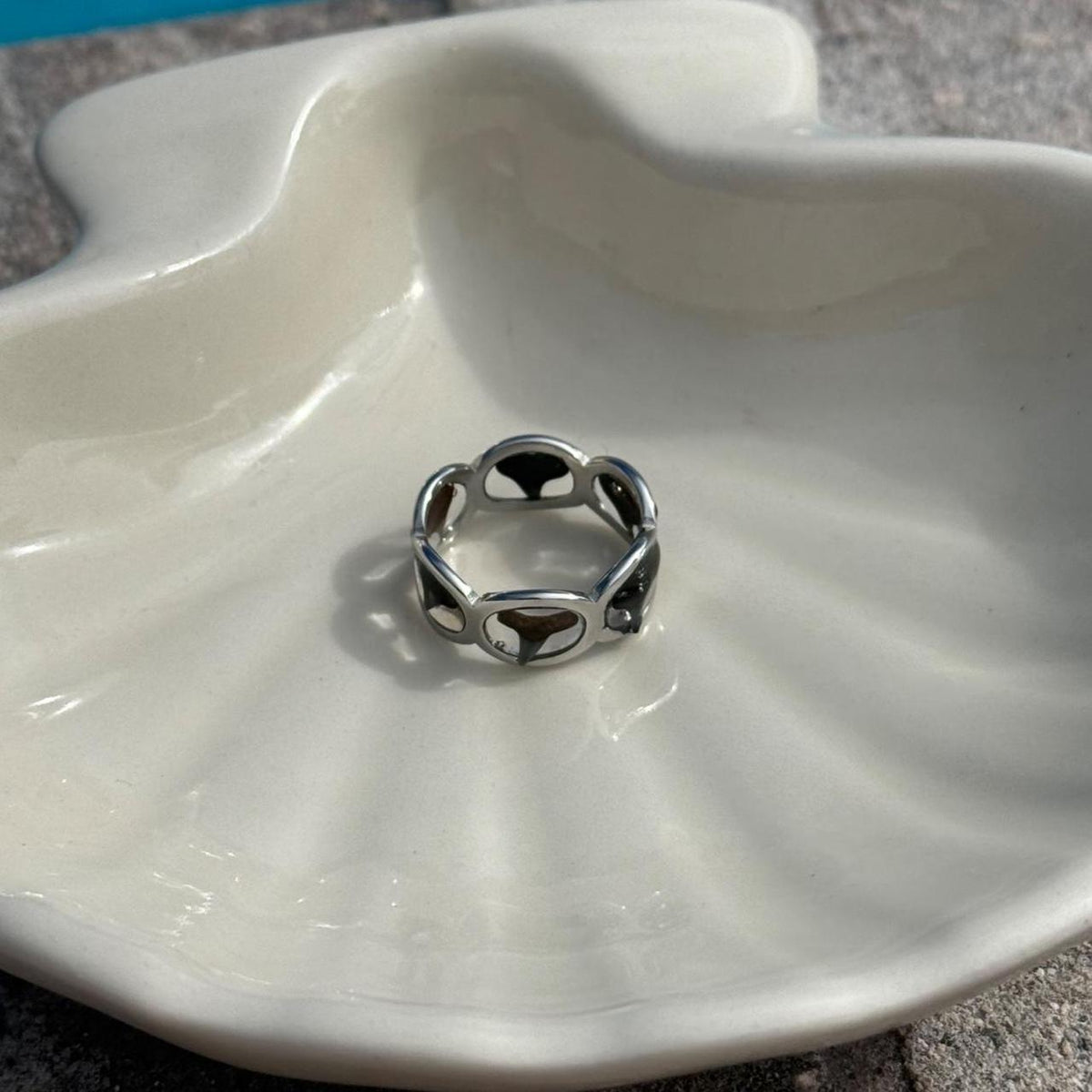 Silver-tone shark tooth ring on ivory dish